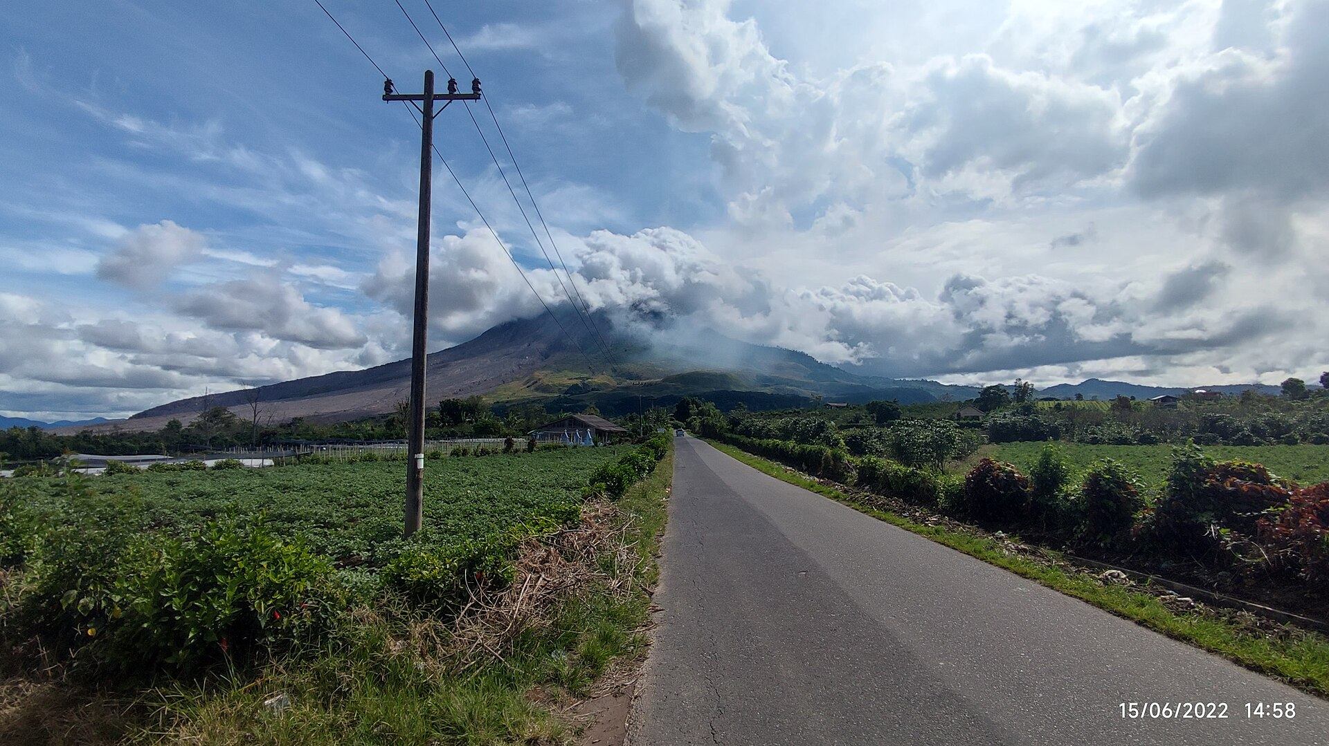 Jalan desa menuju Gunung Sinabung yang puncaknya tertutup awan